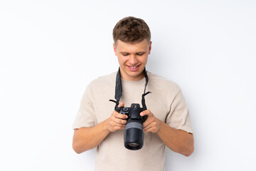 Young handsome man over isolated white background with a professional camera