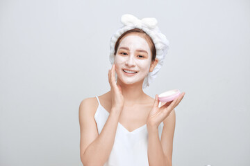 Happy young Asian woman applying facial clay mask and wearing a towel.