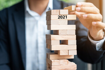 2021 year Goals, Business planning, Risk Management, Solution and strategy Concepts. Businessman hand placing or pulling wooden block on the tower