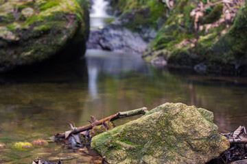 Piedra en primer plano, con cascada al fondo