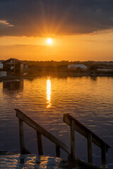 A wooden pier next to a body of water at sunset