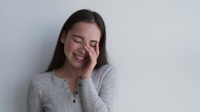 Pretty asian young woman making cute faces, smiling looking at camera with a white background