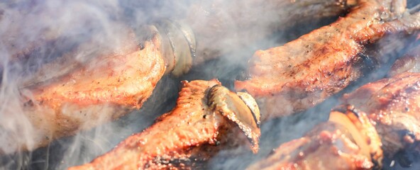Naklejka premium Barbecue skewers with juicy meat cooking in open air in summer. Food banner. 