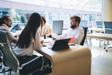 Group of Caucasian partners sitting at table desk and cooperating on business ideas for together brainstorming, experienced managers discussing documents information planning startup strategy