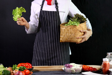 Chef wearing apron, holding fresh green vegetables, healthy food concept