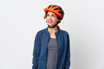 Young cyclist woman isolated on white background thinking an idea while looking up