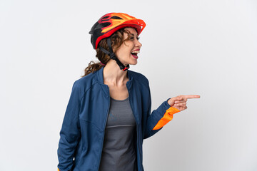 Young cyclist woman isolated on white background pointing finger to the side and presenting a product