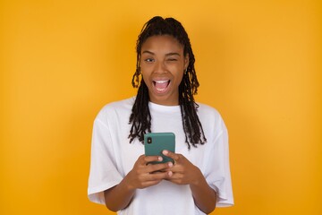 Portrait of Young dark skinned woman with braids hair wearing casual clothes trendy isolated over yellow background ,taking a selfie celebrating success