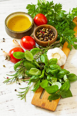 Ingredients for cooking. Herbs spices, olive oil and vegetables on a wooden table.