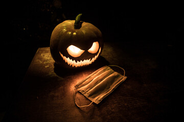 Halloween during Corona virus global pandemic concept. Glowing pumpkins and Covid novel on dark...