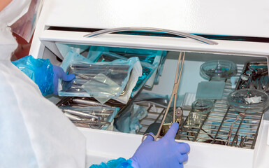 the nurse takes medical instruments from the ultraviolet cabinet for disinfection in the dental...