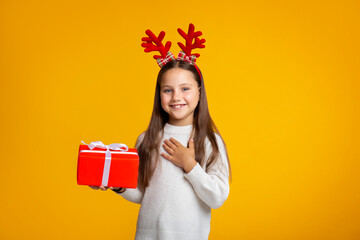 Happy holidays. Smiling girl with horns in sweater holds gift in hand