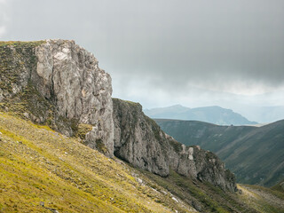 Scenic landscape in Bucegi Mountains with a huge rock formation against a dark cloudy sky.