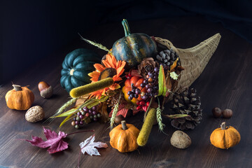 Cornucopia centrepiece filled with autumn decorations against a black background.