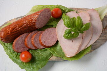 Sliced spicy smoked beef/ pork sausage and turkey pastrami slices. With lettuce leaf and basil,cherry tomatoes.