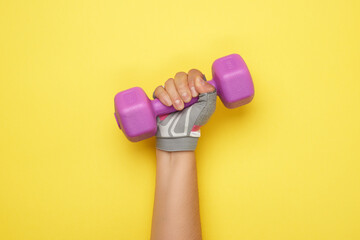 female hand in a pink sports glove holds a purple one kilogram dumbbell