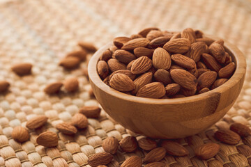 Fresh almonds nut in wooden bowl on Water hyacinth placemats.