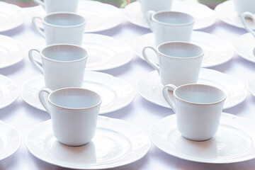 Fototapeta na wymiar Set of Empty white ceramic tea or coffee cup and saucers. Group of empty cups stacked in rows for serving coffee in restaurant.