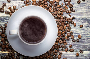 The cup of hot coffee with coffee beans on the table