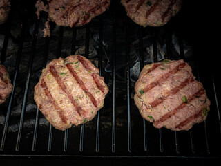 Fresh meat cutlets in a frying grill. Preparing a batch of ground beef patties or frikadeller on grill or BBQ.