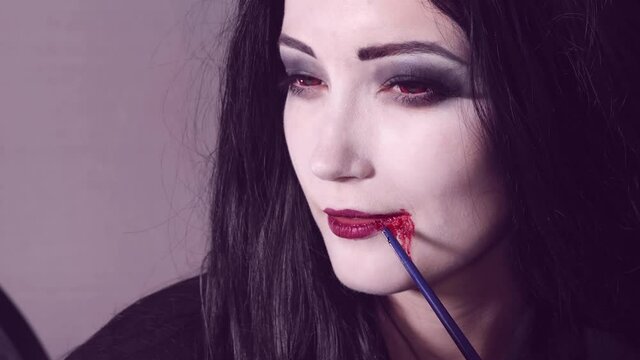 Young woman doing halloween makeup with blod