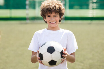 Boy holding soccer ball on the field