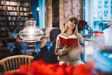 Fototapeta na wymiar Stylish woman in cap sitting in bookshop