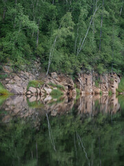 Landscape of calm water of the river, hills and sky reflected in water
