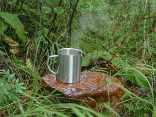iron mug with hot tea in the forest