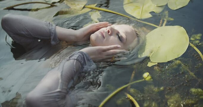 Blond model swims in a lake deep in the forest. Calming view of water. Water Lillies Bobbing On A Lake. River Lily, Green Leaves On The Water