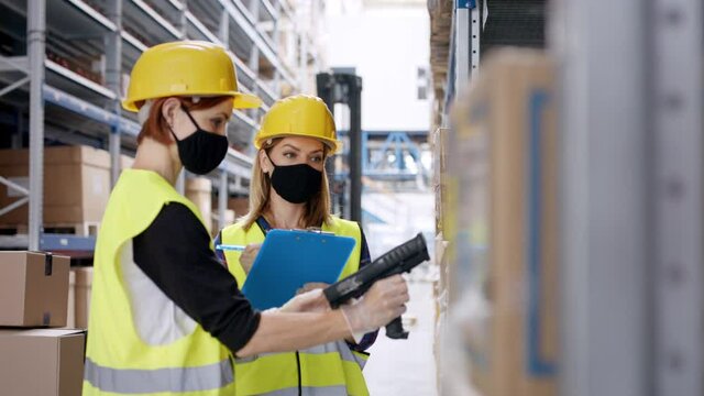 Young women workers with gloves and face mask working in warehouse.