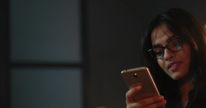 Young woman smiling while having a chat with her friends on whatsapp	