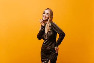 Amazing fair-haired girl in elegant dress smiling to camera. Indoor shot of lovely caucasian model with happy face expression.