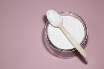 Closeup collagen in a glass with a spoon, on concrete pink background