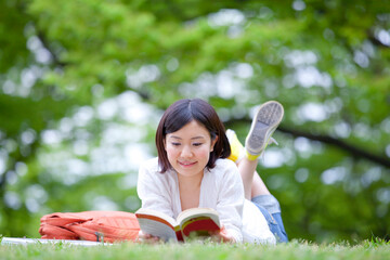 芝生に寝そべり読書する女性