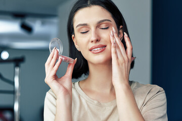 Indoor image of makeup artist girl applying blush on her skin during making online tutorials....