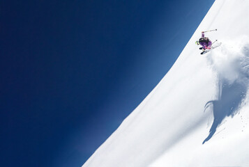 Jumping on skis through steep snow terrain