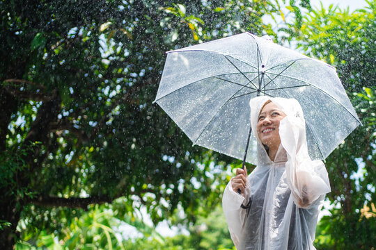 Asian woman smiling and wearing a raincoat on a rainy day