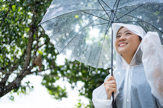 Rainy day Asian women hold umbrellas and wear raincoats.