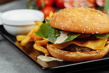 burger with cutlet, cheese and tomatoes. With french fries and burger sauce