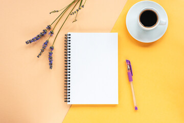 Mock up with blank notepad on yellow background with lavender flowers, coffee cup and pen. Top view, flat lay