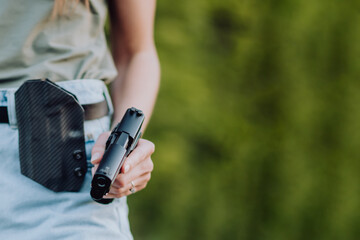 girl in denim shorts and with a gun in his hand posing in the field. Close up