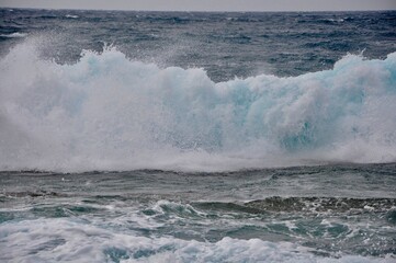 Big wave breaking on the rocks, splashing sea wave.