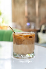 Ice coffee in a tall glass with milk poured over