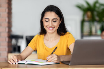 Obraz premium Smiling arab girl working online at cafe