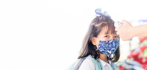 temperature check in school kid girl at school.Open school first health check up measurement.Asian girl measuring body temperature and wearing a face mask back to school.Healthcare medical.Thermometer