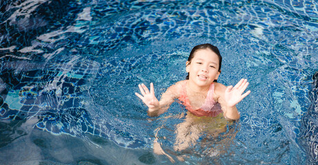 Little girl dancing under the water in the pool.Little ballerinas in ballet outdoor class.Cute little asian girl in swimming pool during a ballet dance class at hotel.