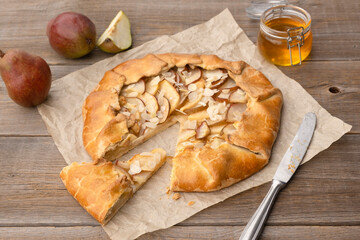 Pear pie with honey and nuts cut into pieces on an old wooden table. Homemade autumn baked goods.