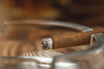 Lighted cigar in an ashtray close up