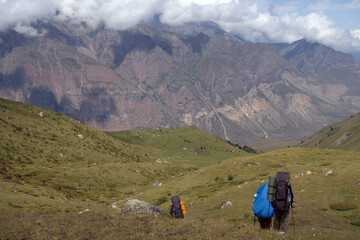 Fototapeta na wymiar Backpackers trekking in mountains. Tourists hike through the valley. Valley near Bulungu village.
